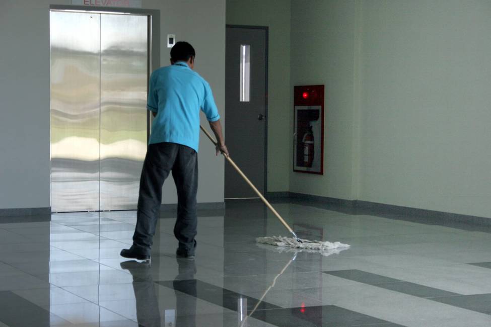 A man clean the floor tile in a building